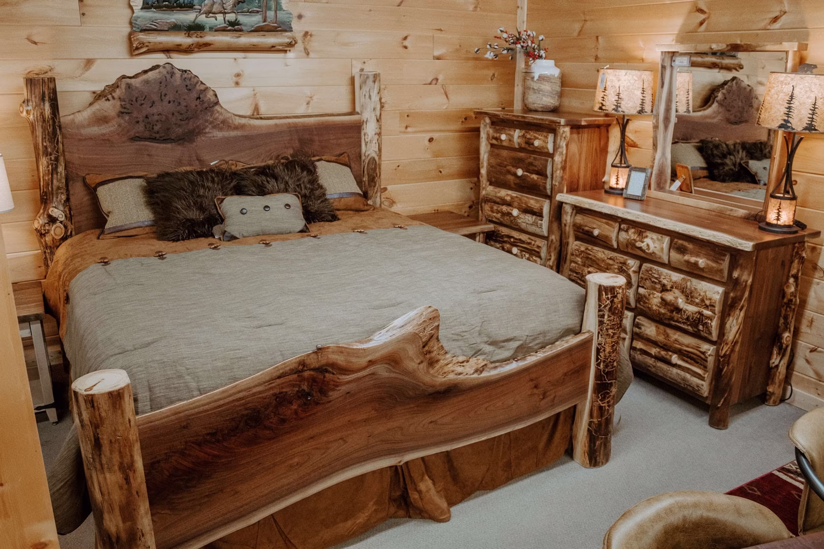 new (72 of 396) A wooden bed with a headboard and footboard, a dresser with mirror and lamps, and wooden walls with framed pictures create a cozy, rustic bedroom setting.
