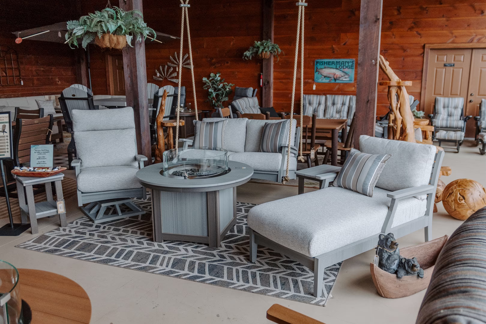 classic-terrace-tropicana-collection-featured-image A wooden room houses a gray sofa, wooden rocking chair, and wooden table with a fire pit, surrounded by plants and decorative objects.