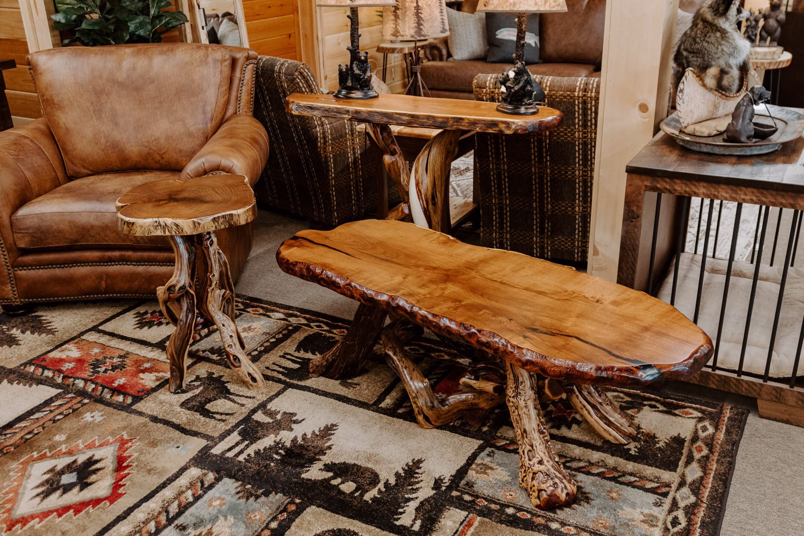 A wooden coffee table with curved top and legs, accompanied by a leather armchair and floral side table, sits on a patterned rug in a cozy living room.
