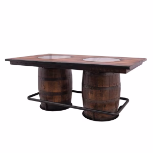 A rustic rectangular wooden table with two circular insets on top, supported by two wooden barrels and a dark metal base.