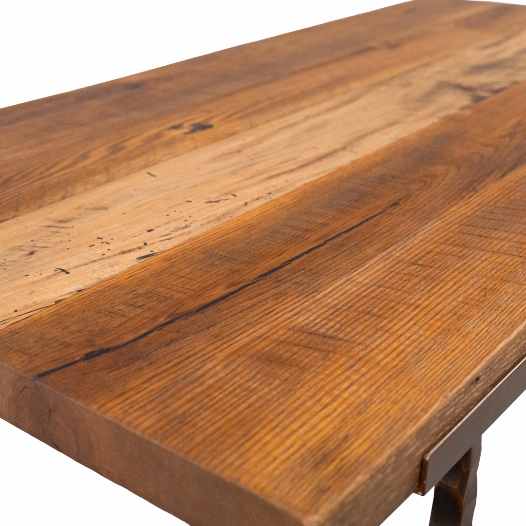 A close-up perspective view of a rustic, light-brown wooden tabletop featuring prominent grain patterns and natural imperfections.