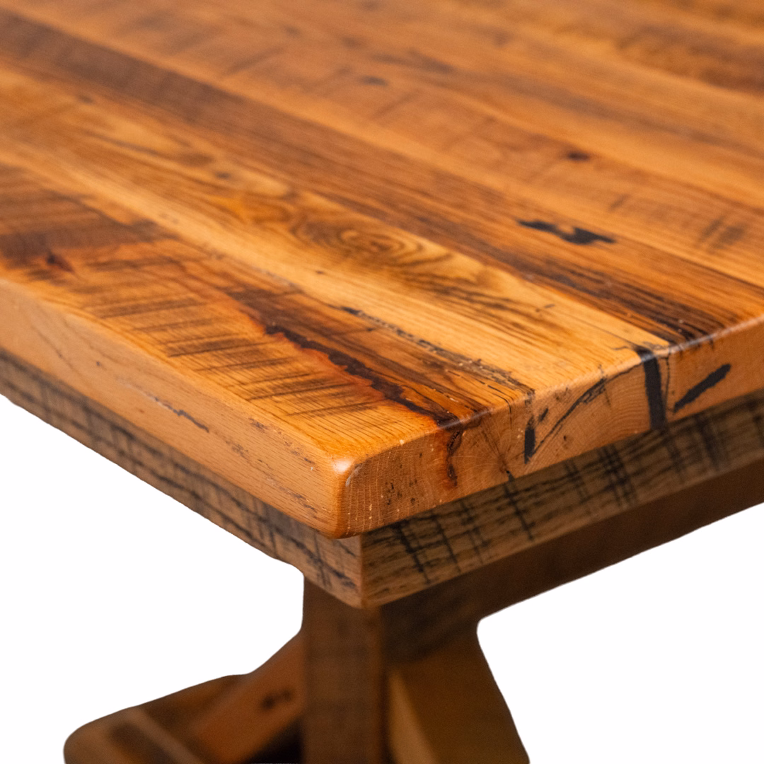 A close-up view of the corner of a polished wooden table featuring a rustic grain with warm brown tones.
