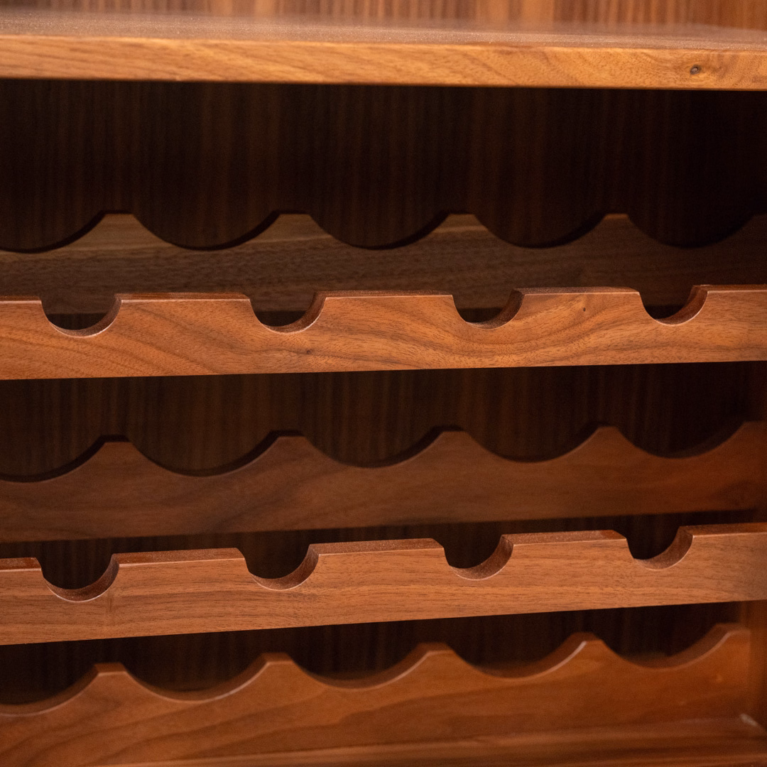 A close-up view of a multi-tiered wooden wine rack with scalloped shelves.