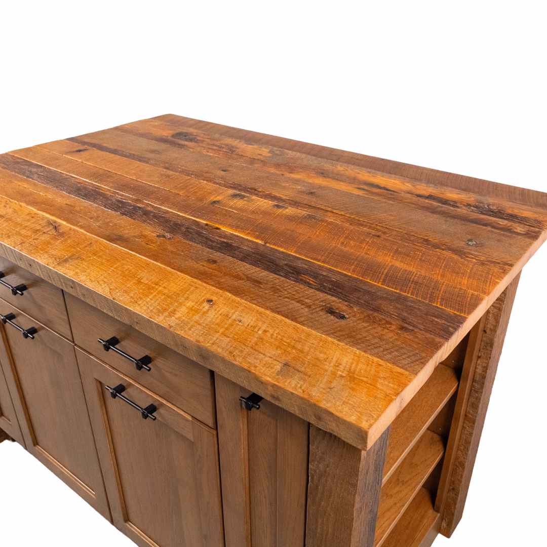 A rustic wooden kitchen island featuring a thick, multi-toned reclaimed wood top, light-colored base cabinets with black handles, and open shelving on the side.